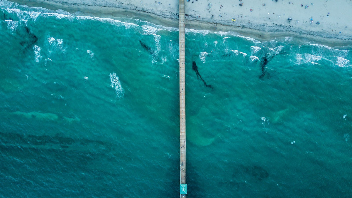 Aerial view looking straight down at the Deerfield Beach International Fishing Pier reaching out over the reef and turquoise water