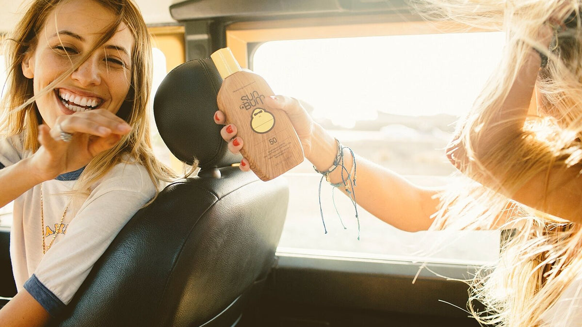 Sun Bum SPF 50 sunscreen lotion passed between friends on a golden-hour road trip