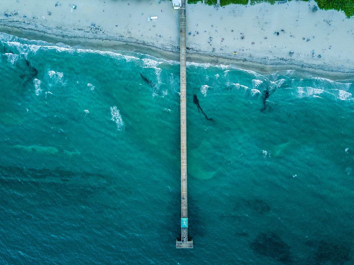 Aerial view looking straight down at the Deerfield Beach International Fishing Pier reaching out over the reef and turquoise water