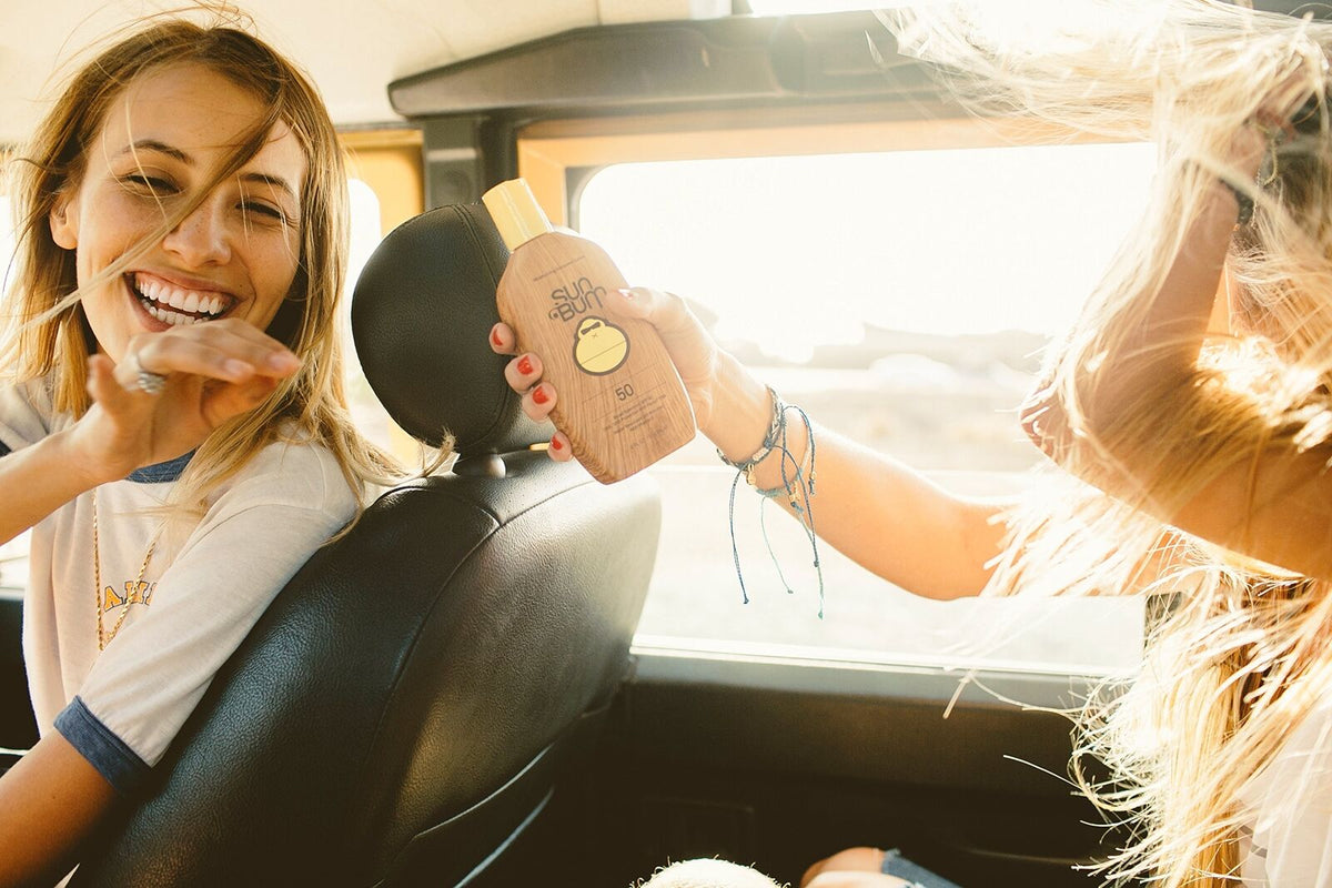 Sun Bum SPF 50 sunscreen lotion passed between friends on a golden-hour road trip