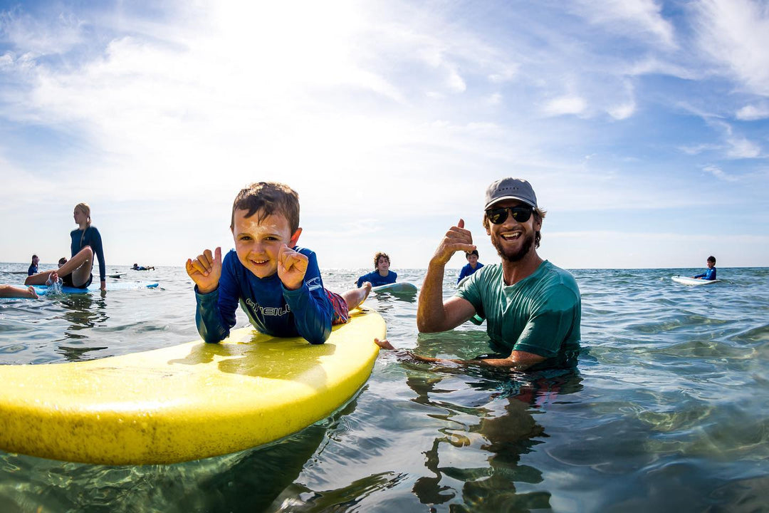 Island Water Sports instructor cheering on a young surfer during a lesson